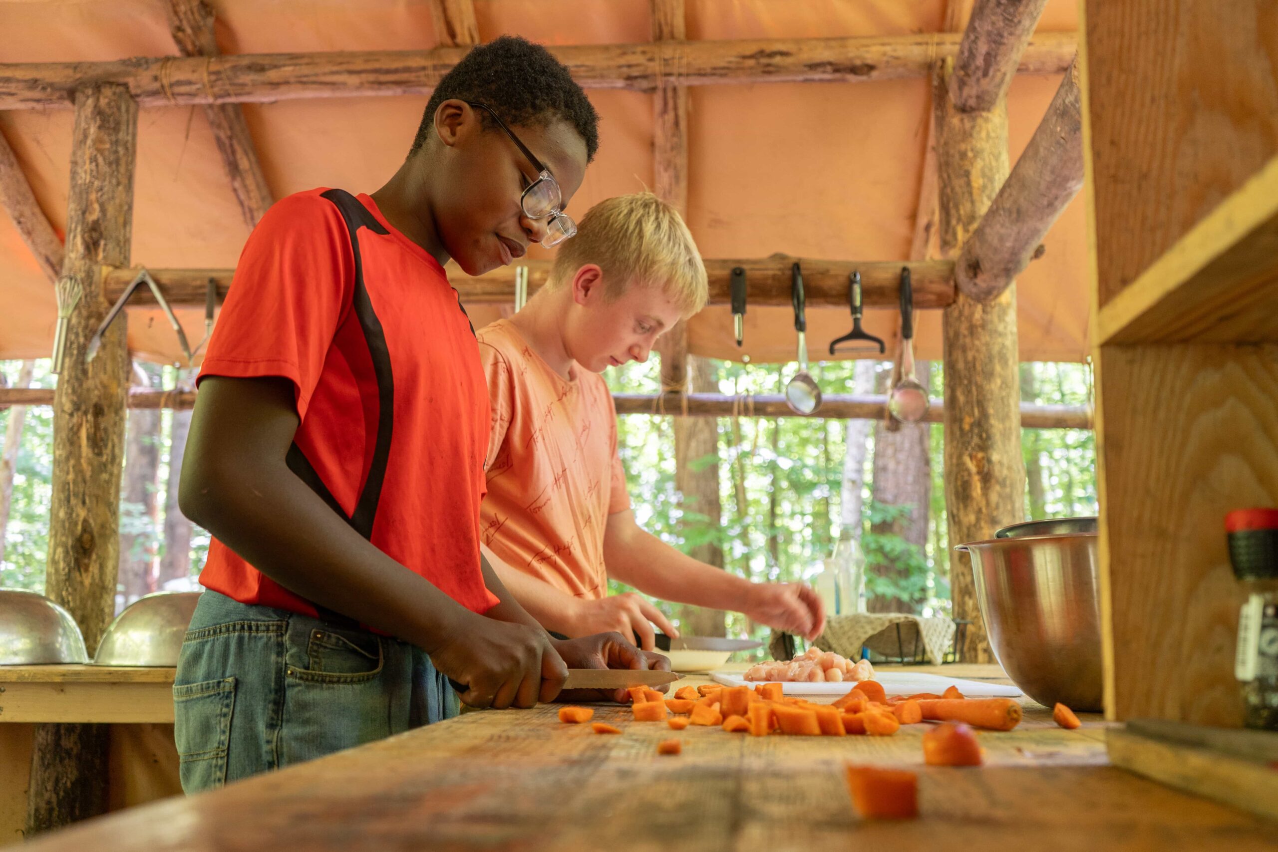Two Fair Play Camp boys preparing vegetables in an outdoor kitchen