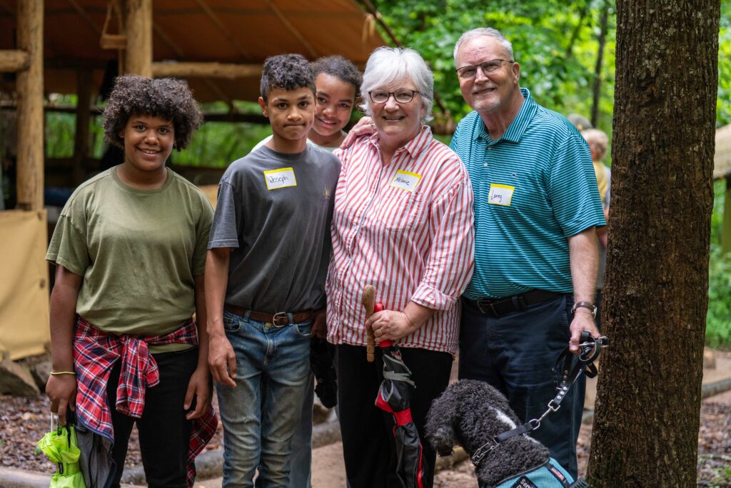Three Fair Play Camp boys with visiting couple and service dog at camp Three Fair Play Camp boys with visiting couple and service dog at camp
