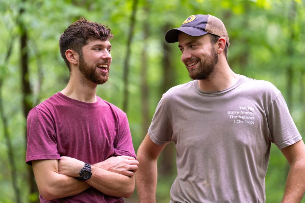 Two Fair Play Camp team members talking in the woods Two Fair Play Camp team members talking in the woods