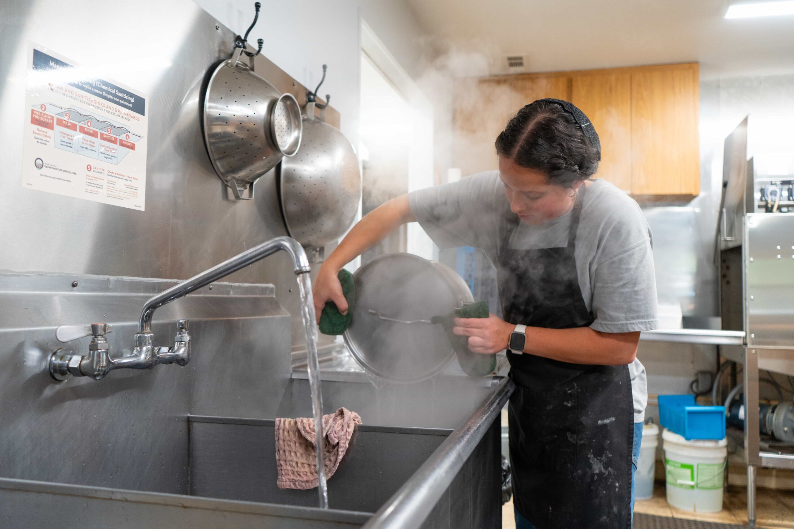 Fair Play Camp cook washing a large pot in the camp kitchen