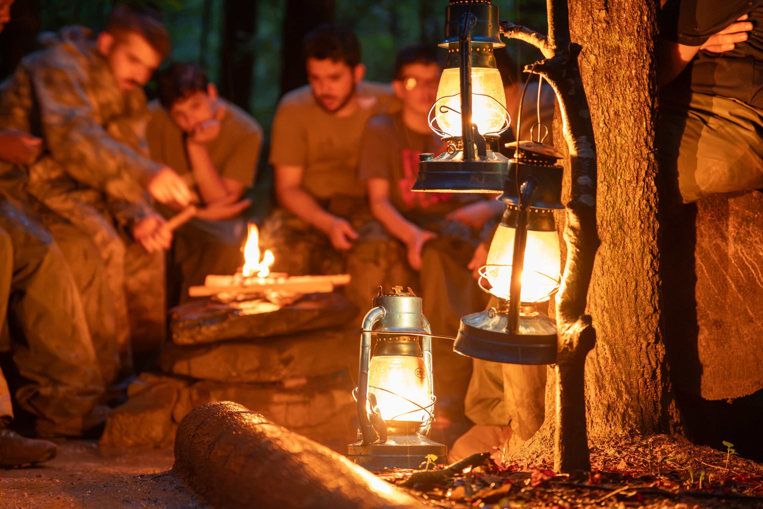Fair Play Chiefs and boys gathered around a campfire by lantern light